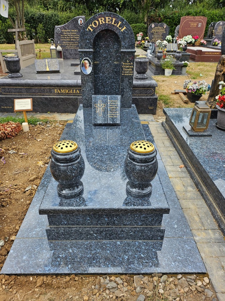 Polished blue pearl granite arched niche headstone with ceramic portrait, open book carving, gold lettering, matching vases and tiered full-length grave slab at Cheshunt Cemetery, Hertfordshire, memorial installation