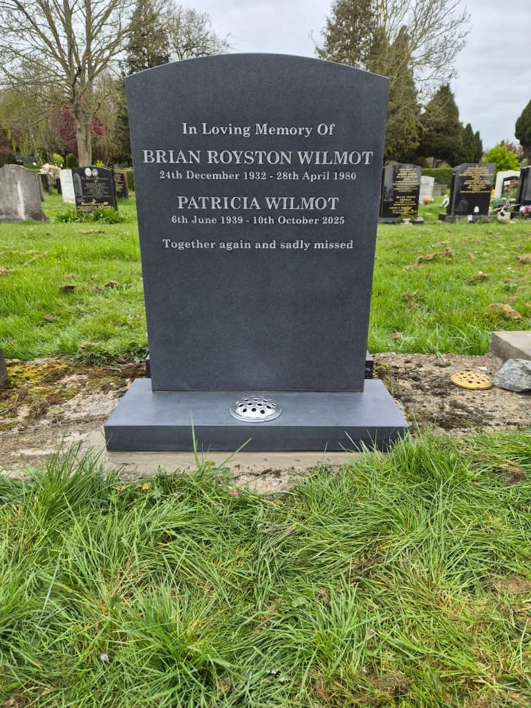 Polished dark grey granite arched-top headstone with silver lettering and rose bowl flower holder on base at Enfield Cemetery, North London — memorial installation