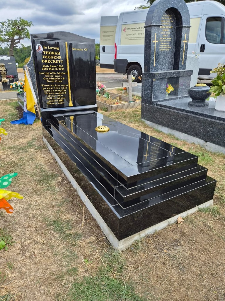 Polished black granite open book headstone with ceramic portrait, gold lettering and tiered full kerb set with ledger slab and flower vase at Forest Park Cemetery, East London, memorial installation