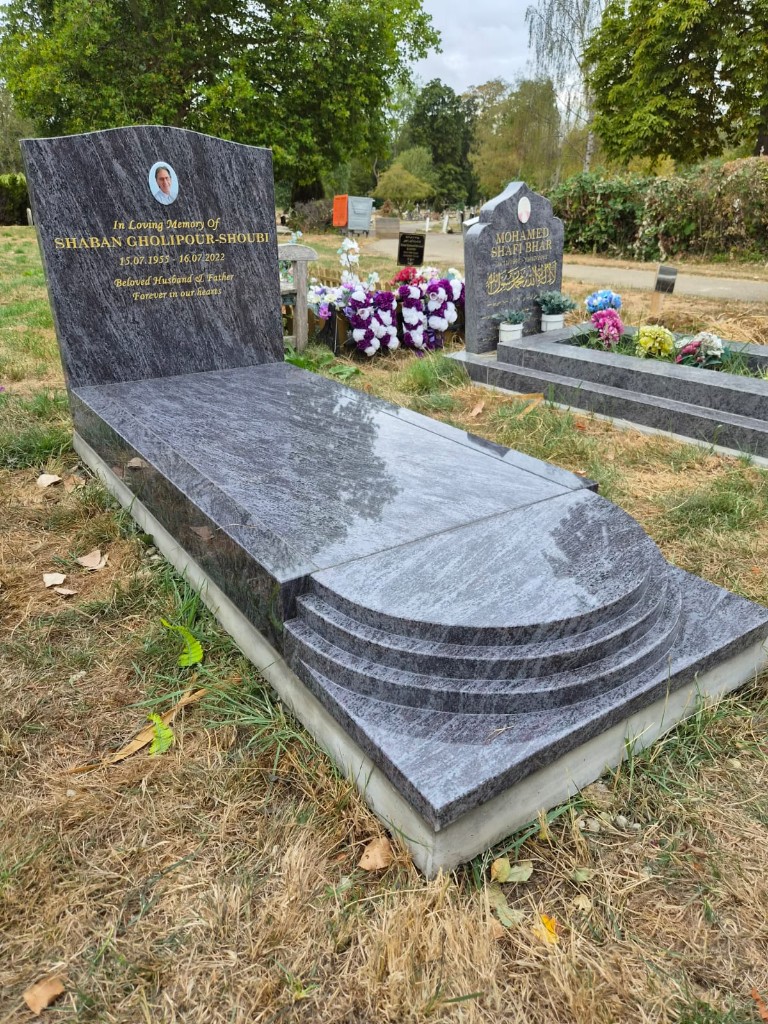 Polished grey-blue granite wave-top headstone with ceramic portrait, gold lettering, full kerb set with ledger slab and tiered semi-circular foot steps at Hendon Cemetery, North London, memorial installation