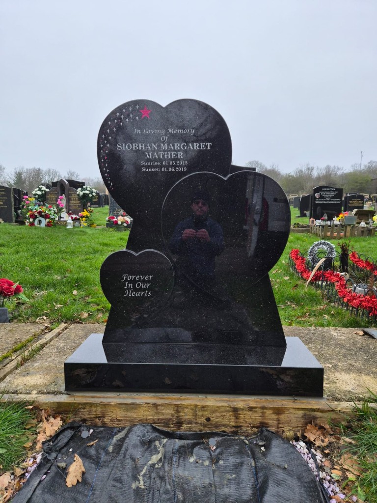 Polished black granite starlight headstone with three overlapping heart shapes and star motif at Islington Cemetery, North London — memorial installation