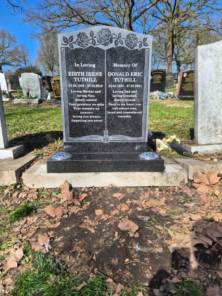 Dark polished granite book-style headstone with rose etching and metal flower holders at North Sheen Cemetery, West London — memorial installation