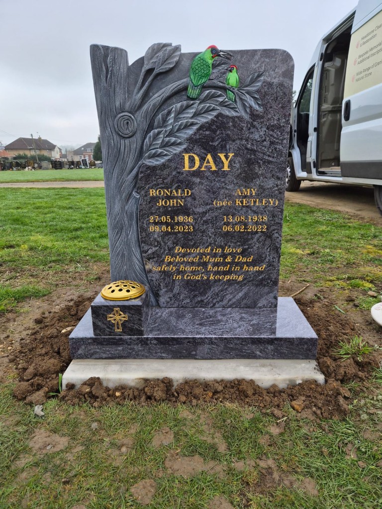 Dark polished granite headstone with carved tree, birds and integrated flower holder at Ongar Cemetery, Essex, memorial installation