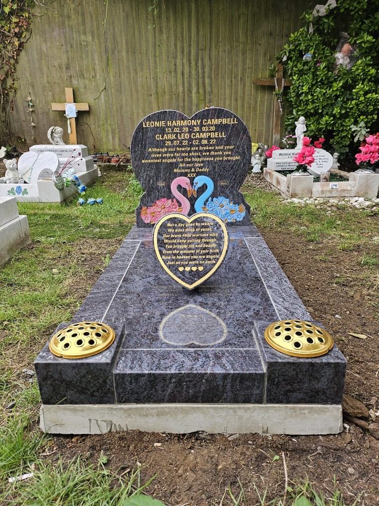 Polished blue-grey veined granite full kerb memorial with heart-shaped headstone, gold lettering, illustrated motif on the upright and matching heart plaque on the ledger at St Pancras Cemetery, North London — memorial installation